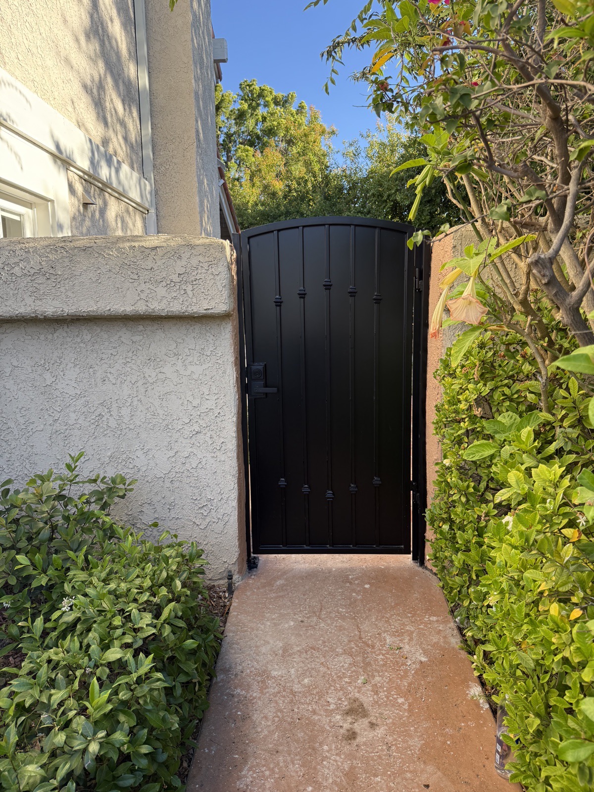 Custom black steel pedestrian gate in a stucco wall